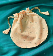 Flat-lay of beige butti embroidered potli with cord drawstring